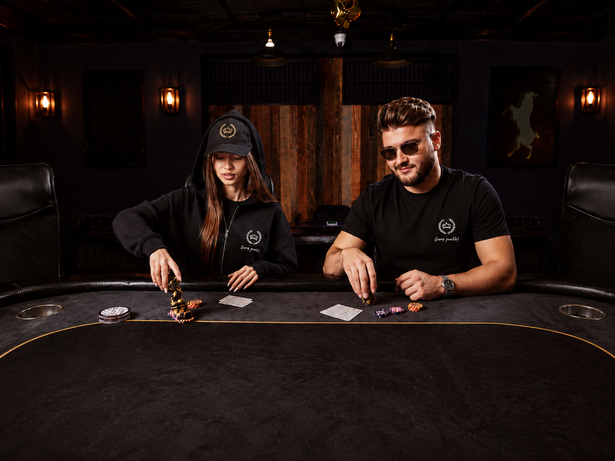 Dwoje modeli w czarnej odzieży EVIVA GAMBLE przy stole pokerowym w klimatycznym klubie